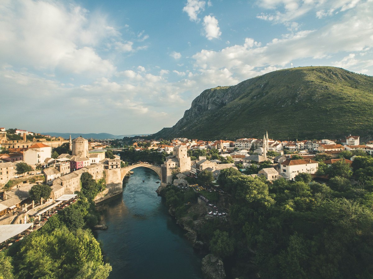 The rebuilt stone arch of Mostar's Old Bridge spanning the green Neretva river between Ottoman era houses