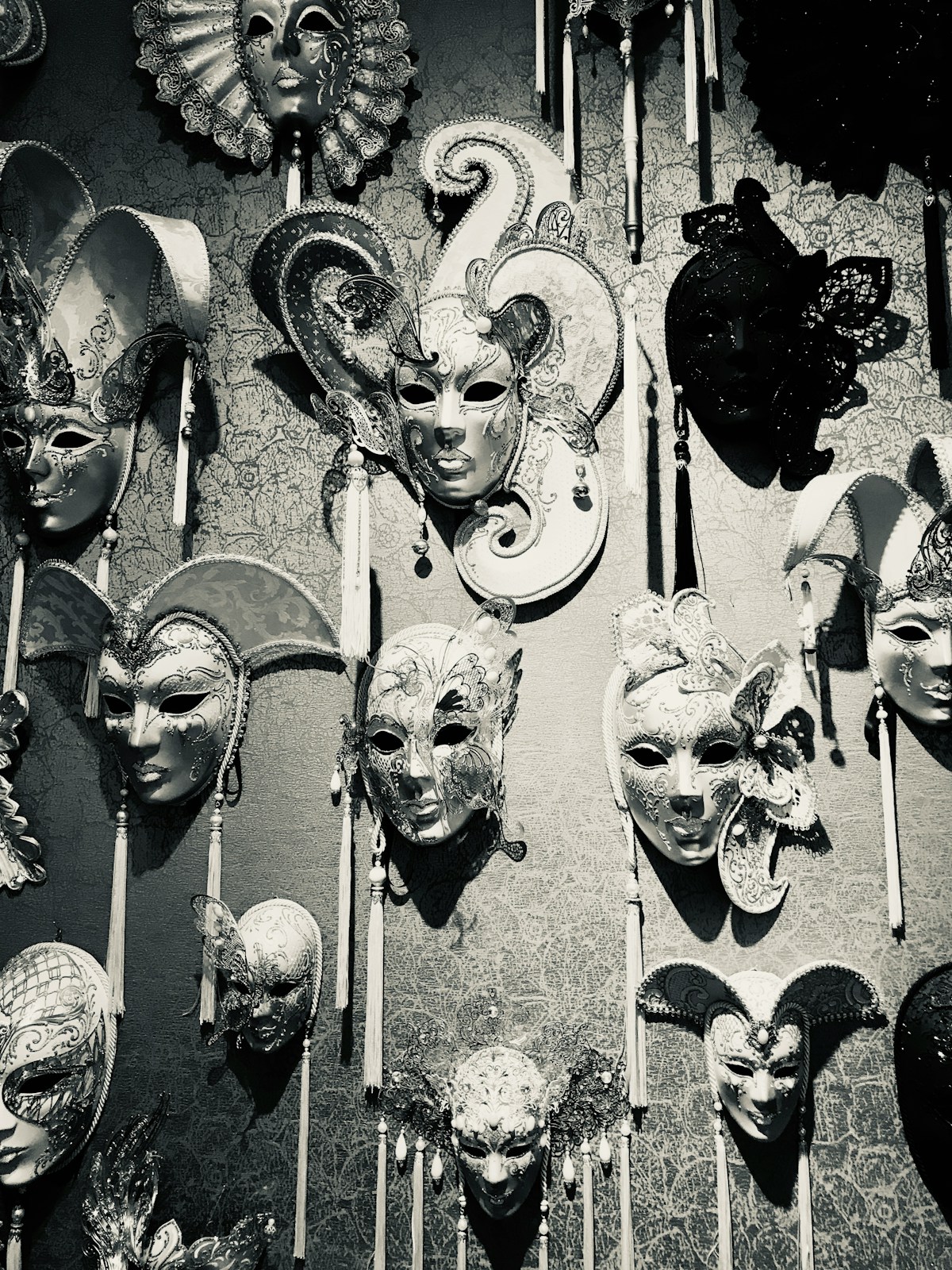 Collection of traditional black and white carnival masks displayed on a wall