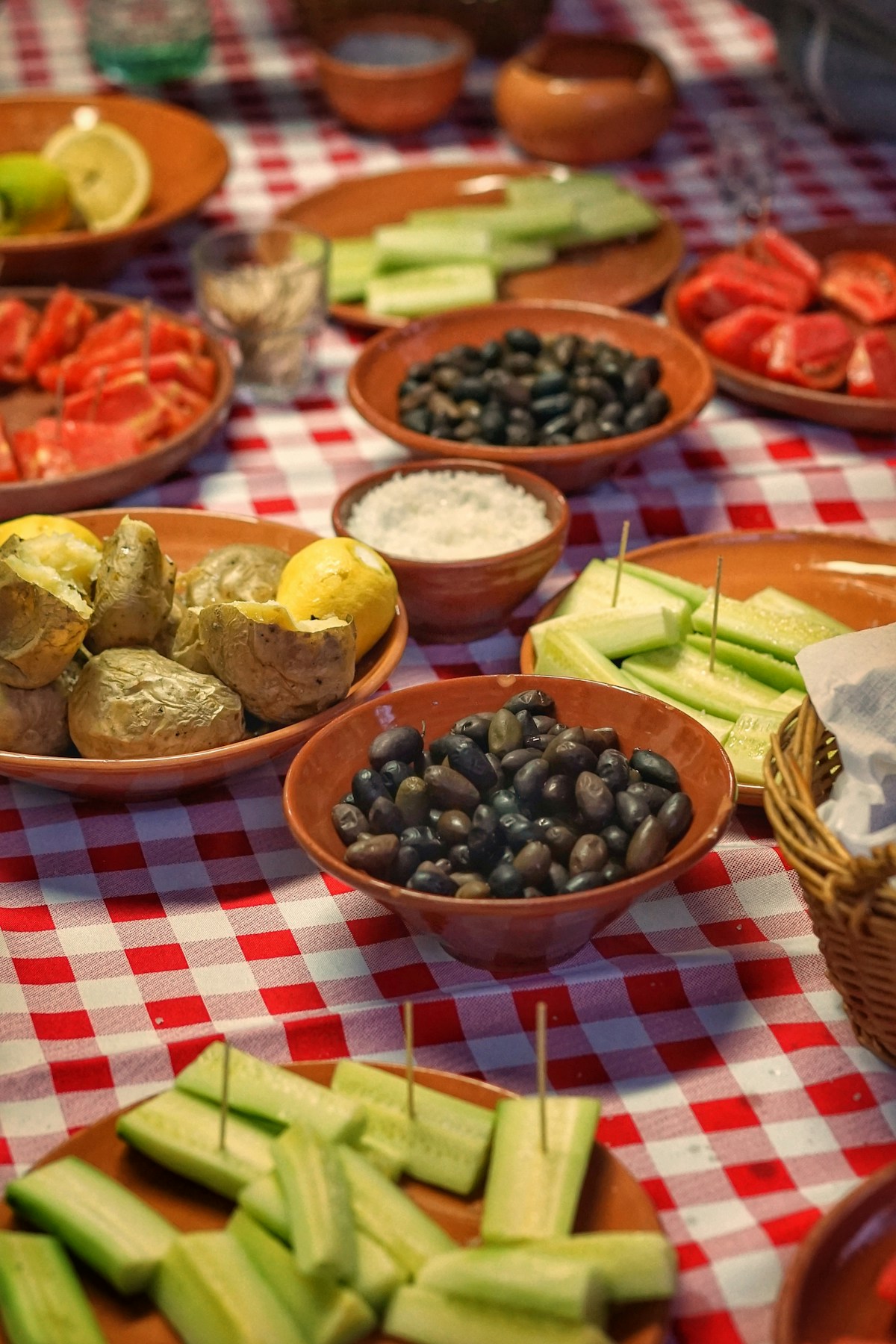Traditional Cretan meze spread with olives, fresh cucumbers, tomatoes, and potatoes on a checkered tablecloth