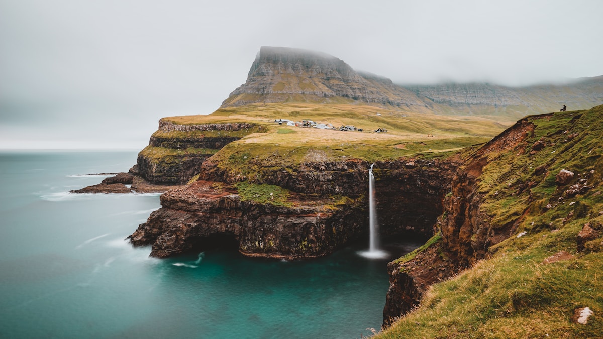 Mulafossur waterfall plunging from a clifftop into the ocean at Gasadalur village in the Faroe Islands