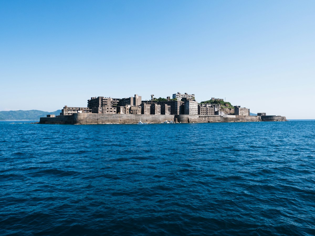Abandoned concrete apartment blocks covering a small rocky island rising out of the open sea