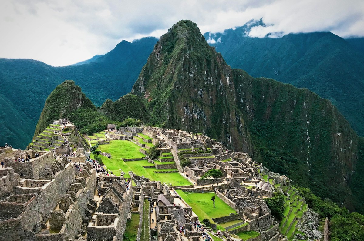 Stone terraces and ruined buildings of Machu Picchu with green peaks rising steeply behind the site