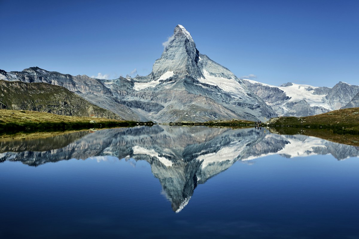 The pyramid of the Matterhorn mirrored in the still water of an alpine lake above Zermatt