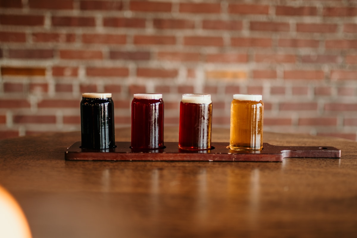 Tasting flight of four small glasses of craft beer in different colors arranged on a wooden tasting paddle at an American brewery