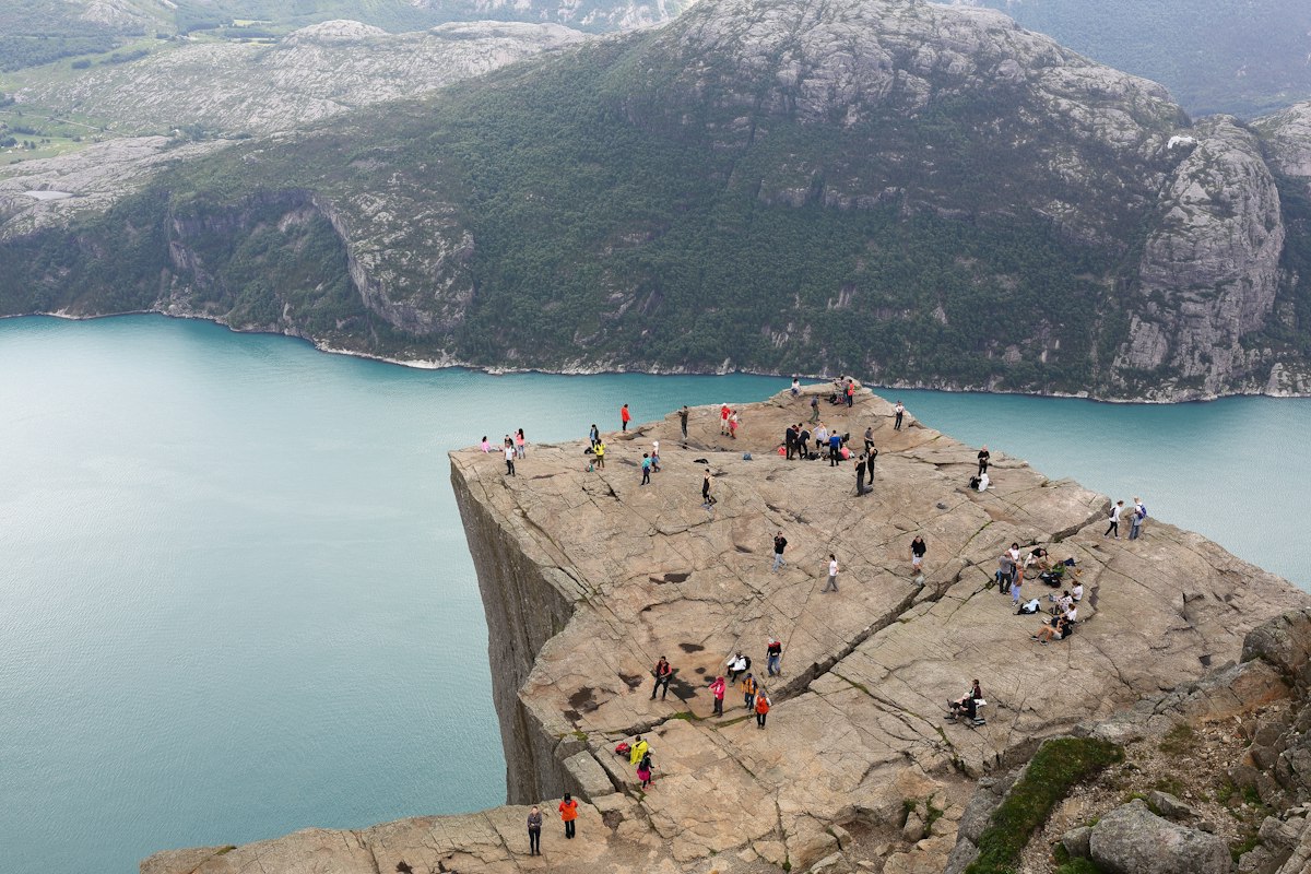 Hikers standing on the flat rock platform of Preikestolen high above the Lysefjord in Norway