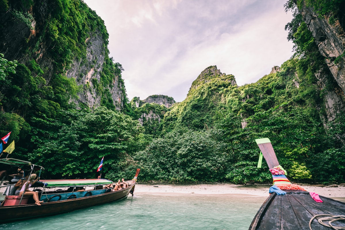Longtail boats moored on Railay Beach in Krabi, Thailand, with dramatic limestone cliffs in the background