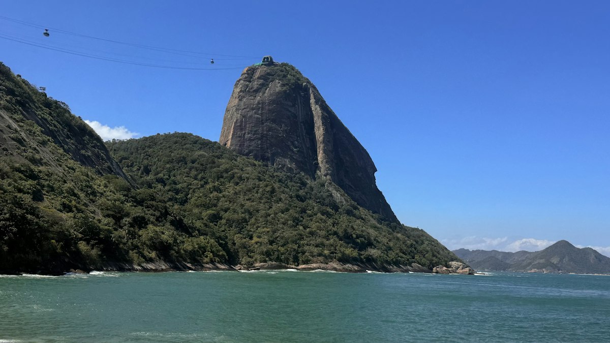 The granite dome of Sugarloaf Mountain rising above Rio de Janeiro's bay with cable car wires crossing the sky