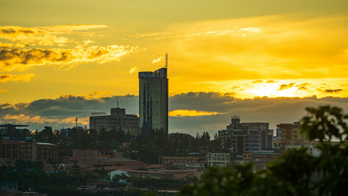 Kigali skyline at sunset with high rise towers silhouetted against a golden sky above the city's green hills