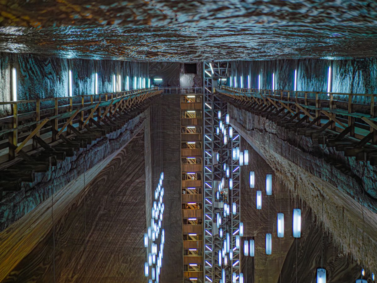 Vast underground salt mine chamber with long vertical light tubes hanging from the ceiling