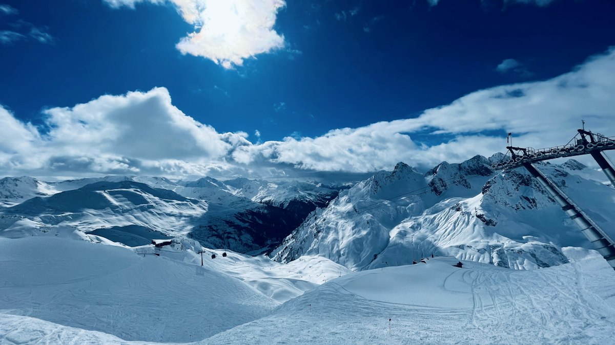 Snow covered mountain ridge with a ski lift line running up it under heavy clouds