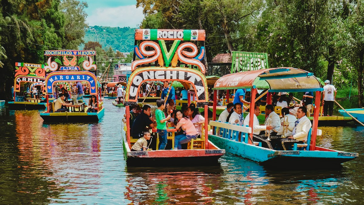 Brightly painted trajinera boats crowded with passengers on the green canals of Xochimilco